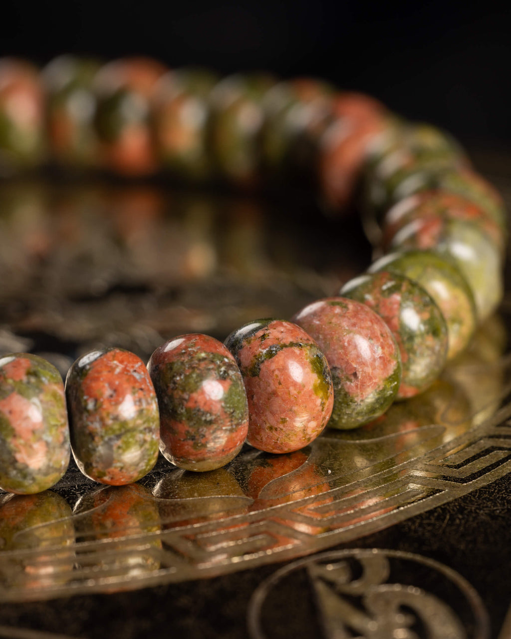 Pulsera de Jaspe Unakita en perspectiva, cuentas alineadas sobre soporte grabado