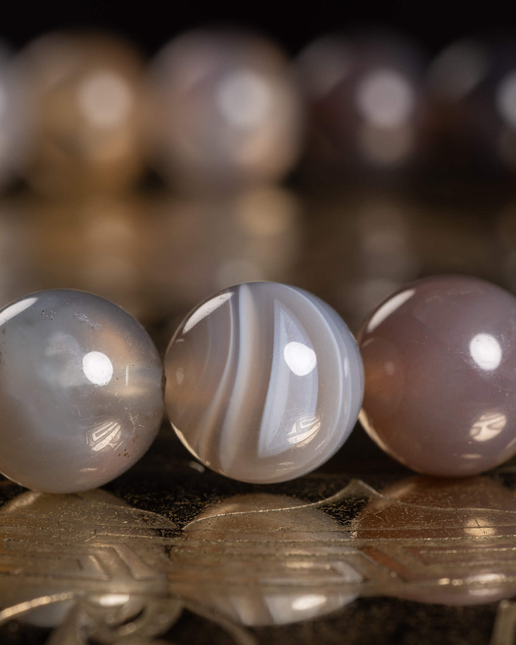 Detalle macro de las cuentas de Ágata Botsuana en tonos gris y café