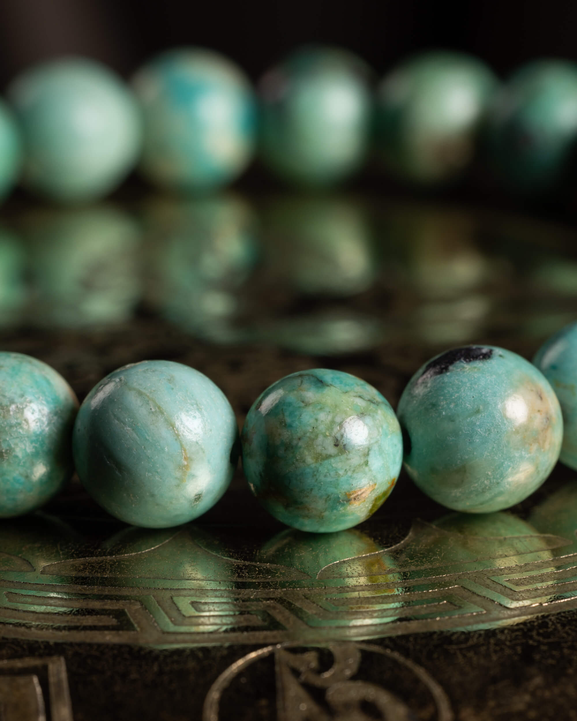 Pulsera de Turquesa Peruana en perspectiva, curva de cuentas sobre soporte grabado
