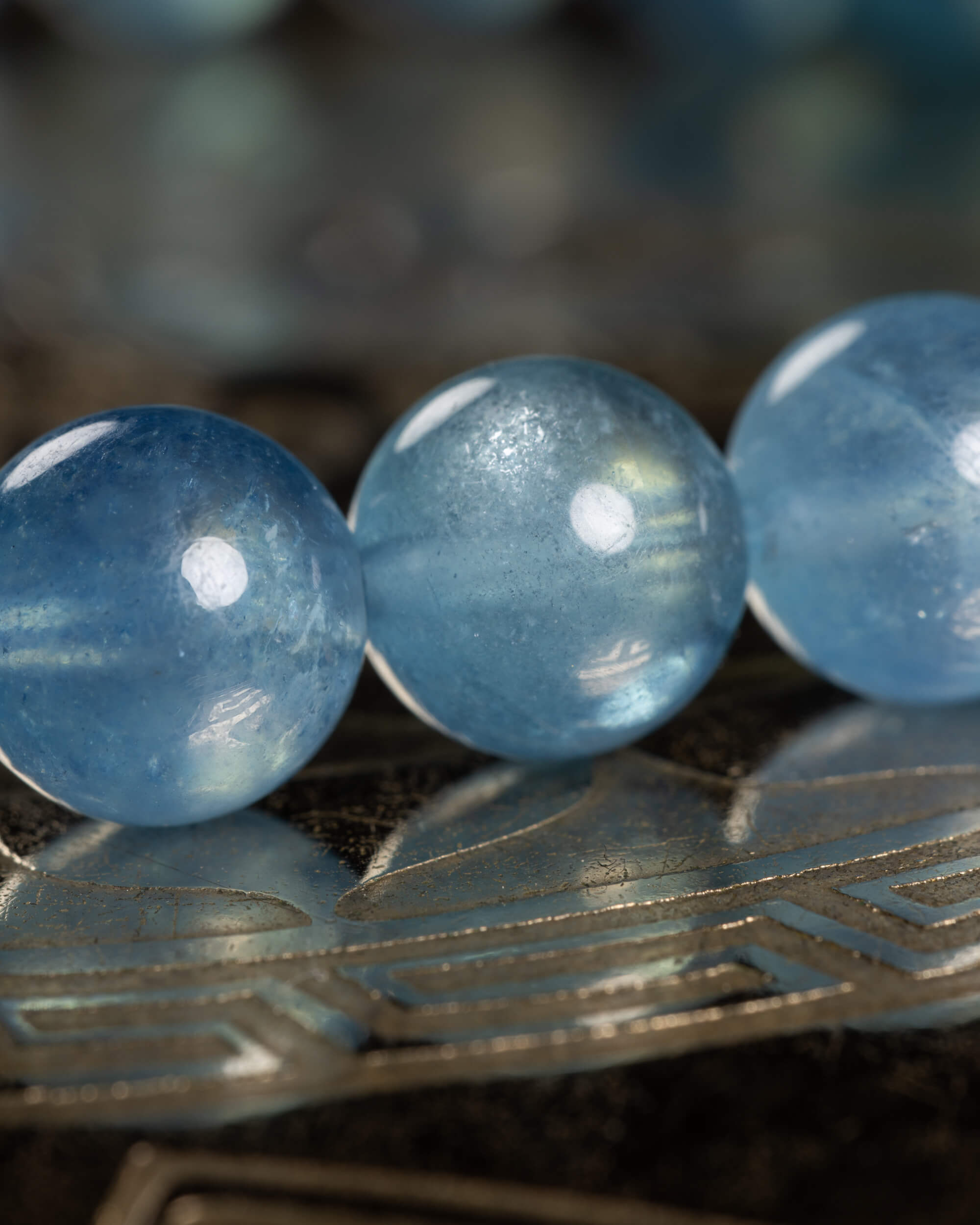 Detalle macro de tres cuentas de Aguamarina, translúcidas con brillo azul claro