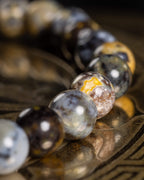 Pulsera de Jaspe Oceánico Amarillo en curva, cuentas moteadas sobre placa oscura