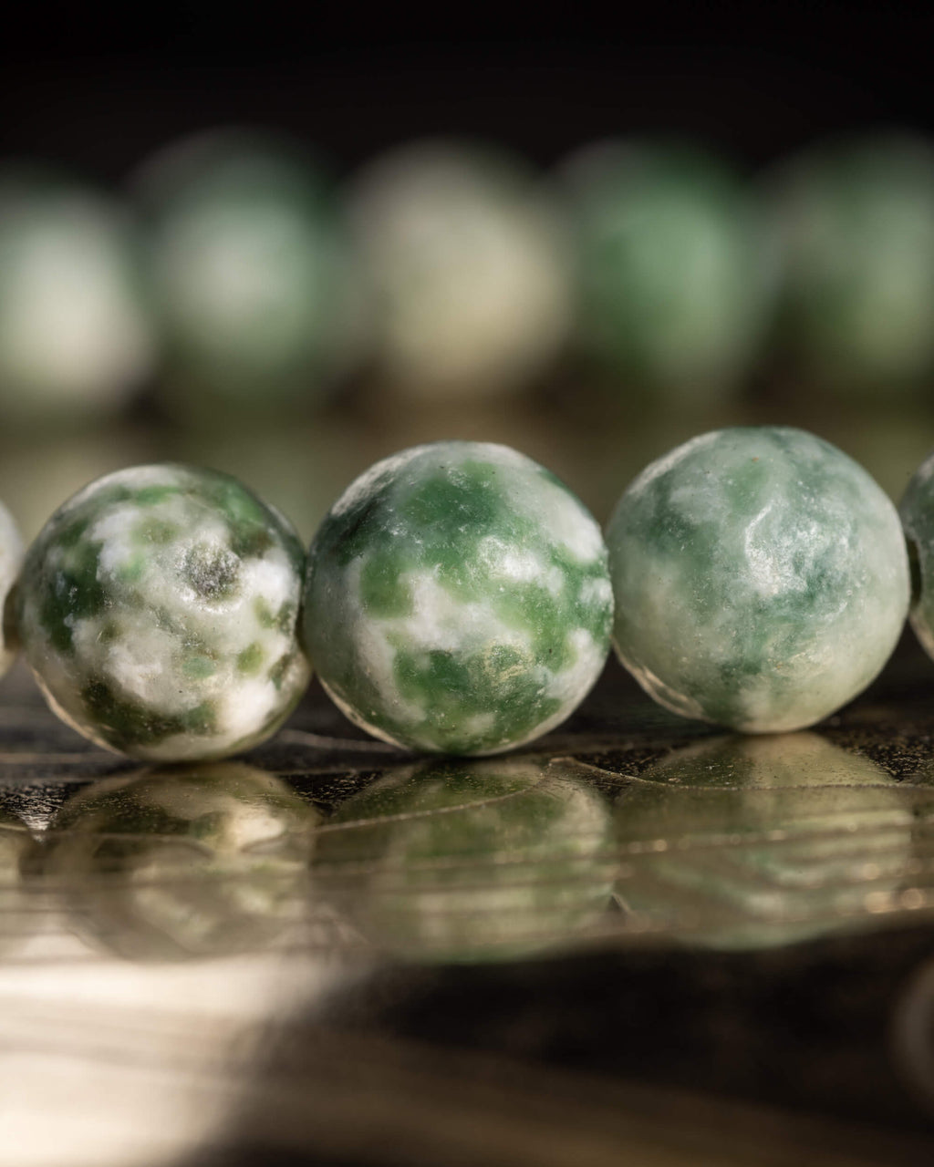 Detalle macro de las cuentas de Ágata Árbol con veta verde sobre madera oscura