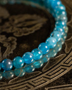 Pulsera de Apatita Azul en ángulo, cuentas reflejadas en superficie metálica
