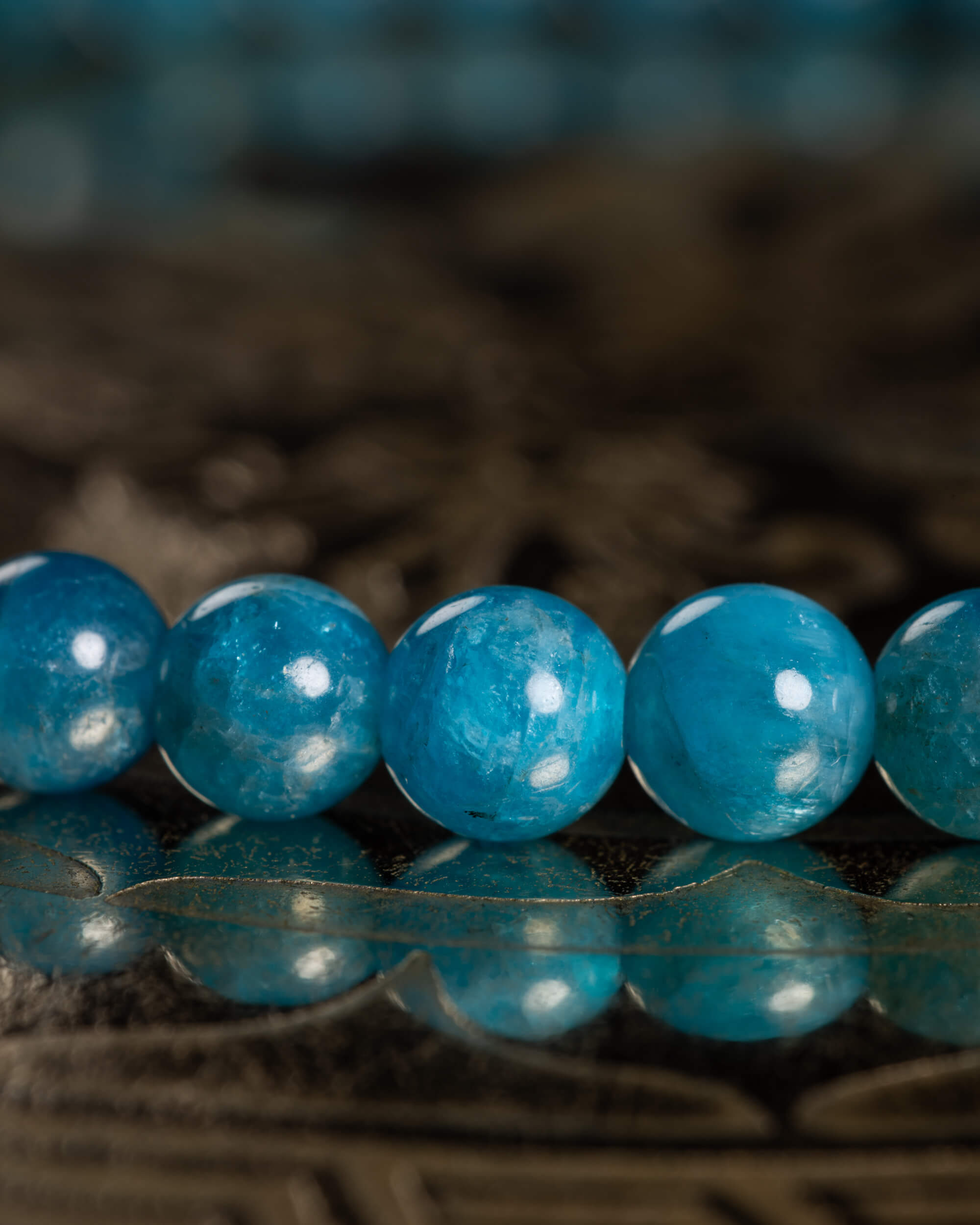 Detalle macro de cinco cuentas de Apatita Azul con textura translúcida
