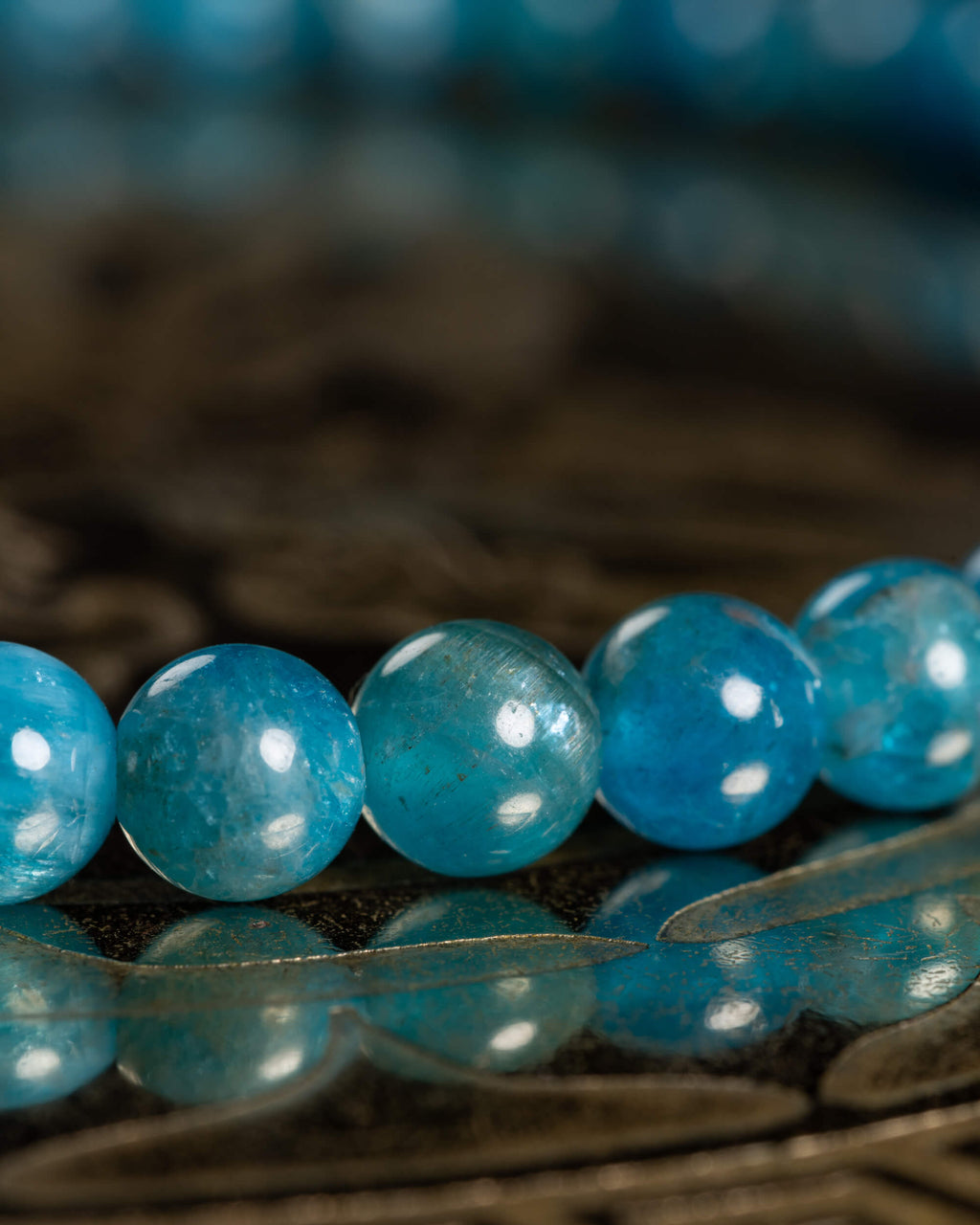Detalle macro de las cuentas de Apatita Azul con brillo translúcido sobre madera