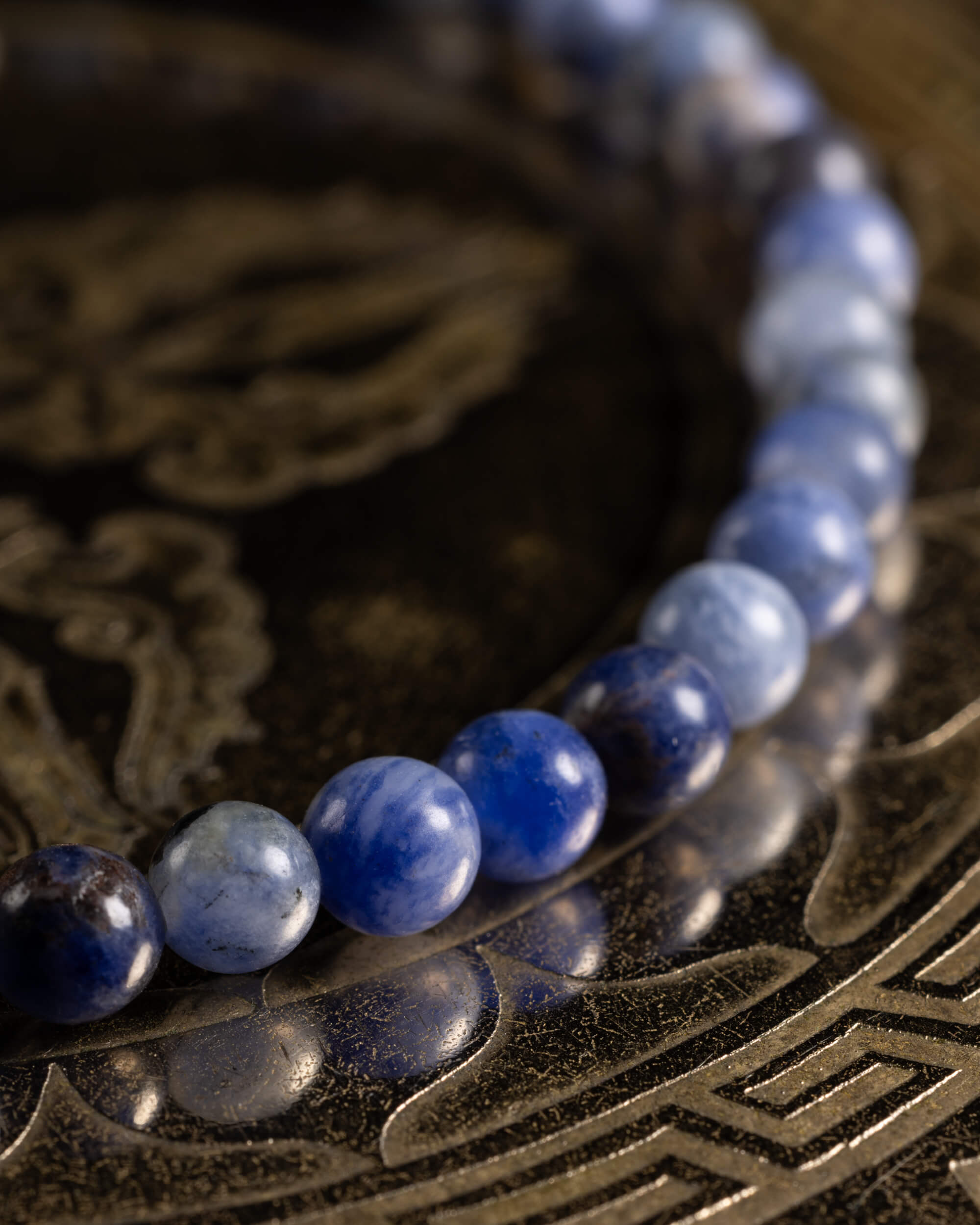 Pulsera de Sodalita en ángulo, cuentas azul y gris sobre superficie metálica