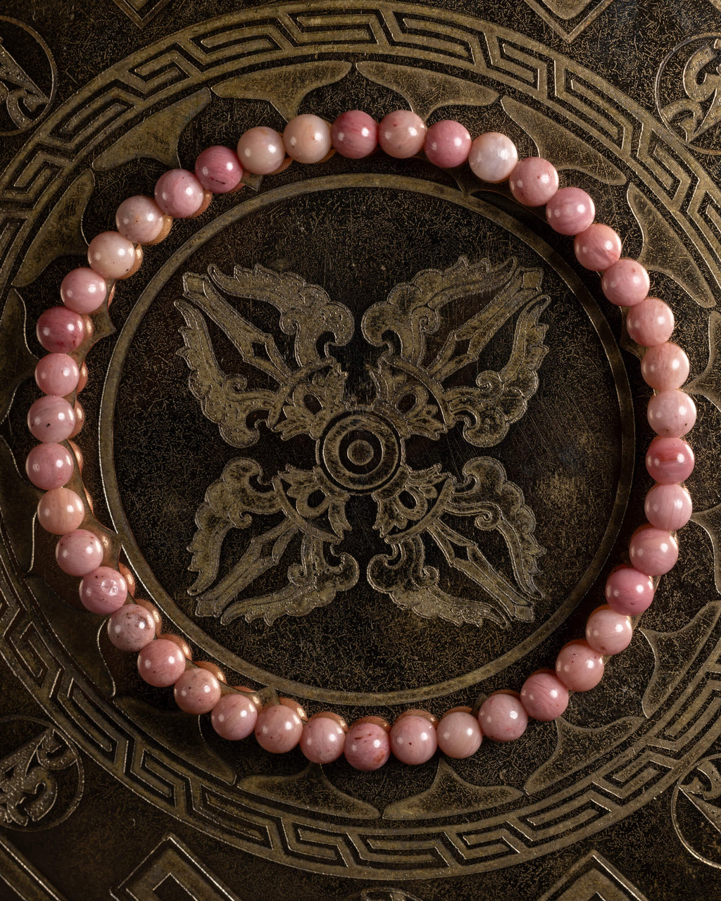 Pulsera de Rodonita Rosa de 4 mm, pieza completa sobre bandeja metálica grabada