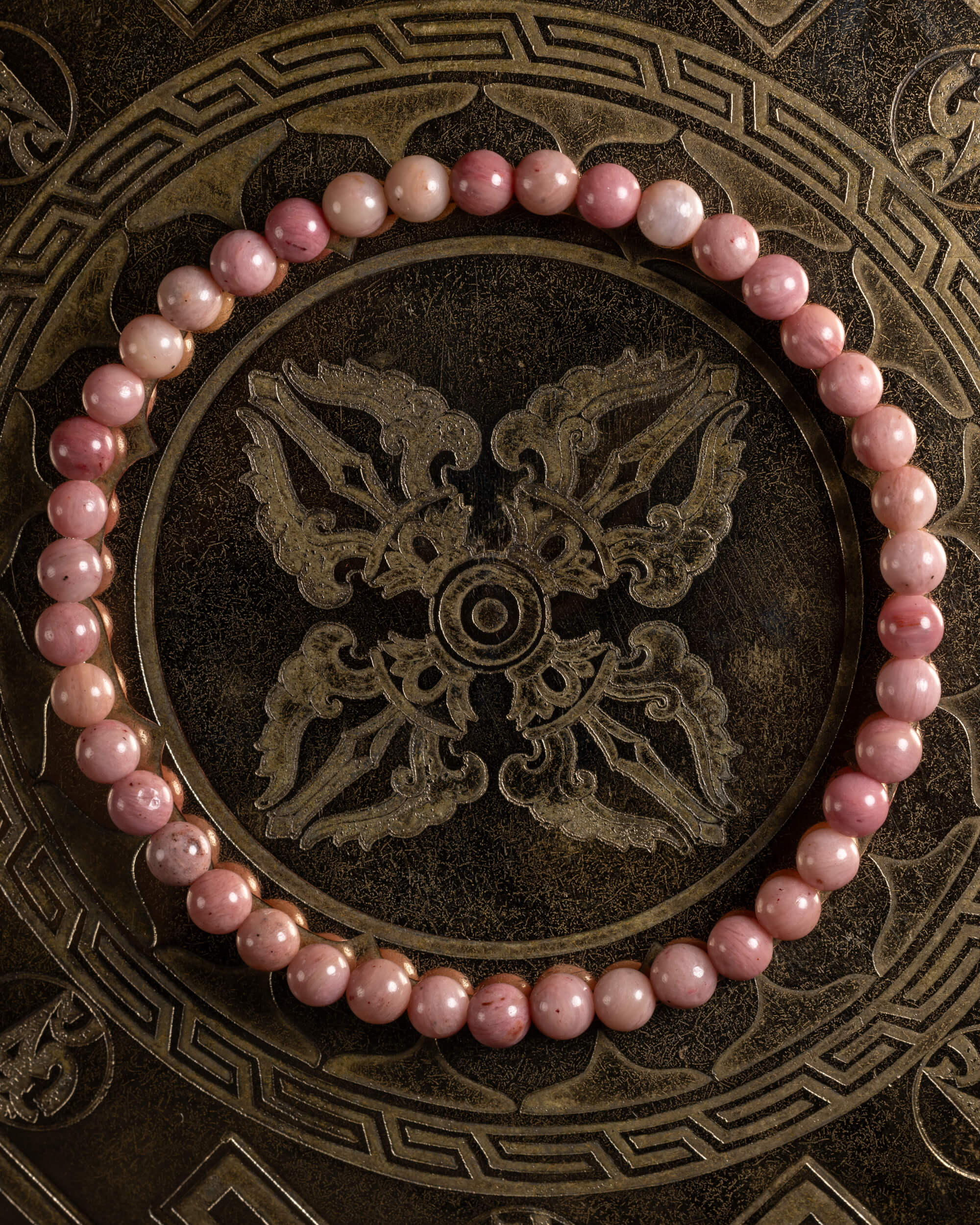 Pulsera de Rodonita Rosa de 4 mm, pieza completa sobre bandeja metálica grabada