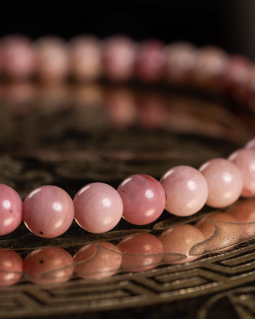 Detalle macro de las cuentas rosa pálido de Rodonita sobre bandeja metálica