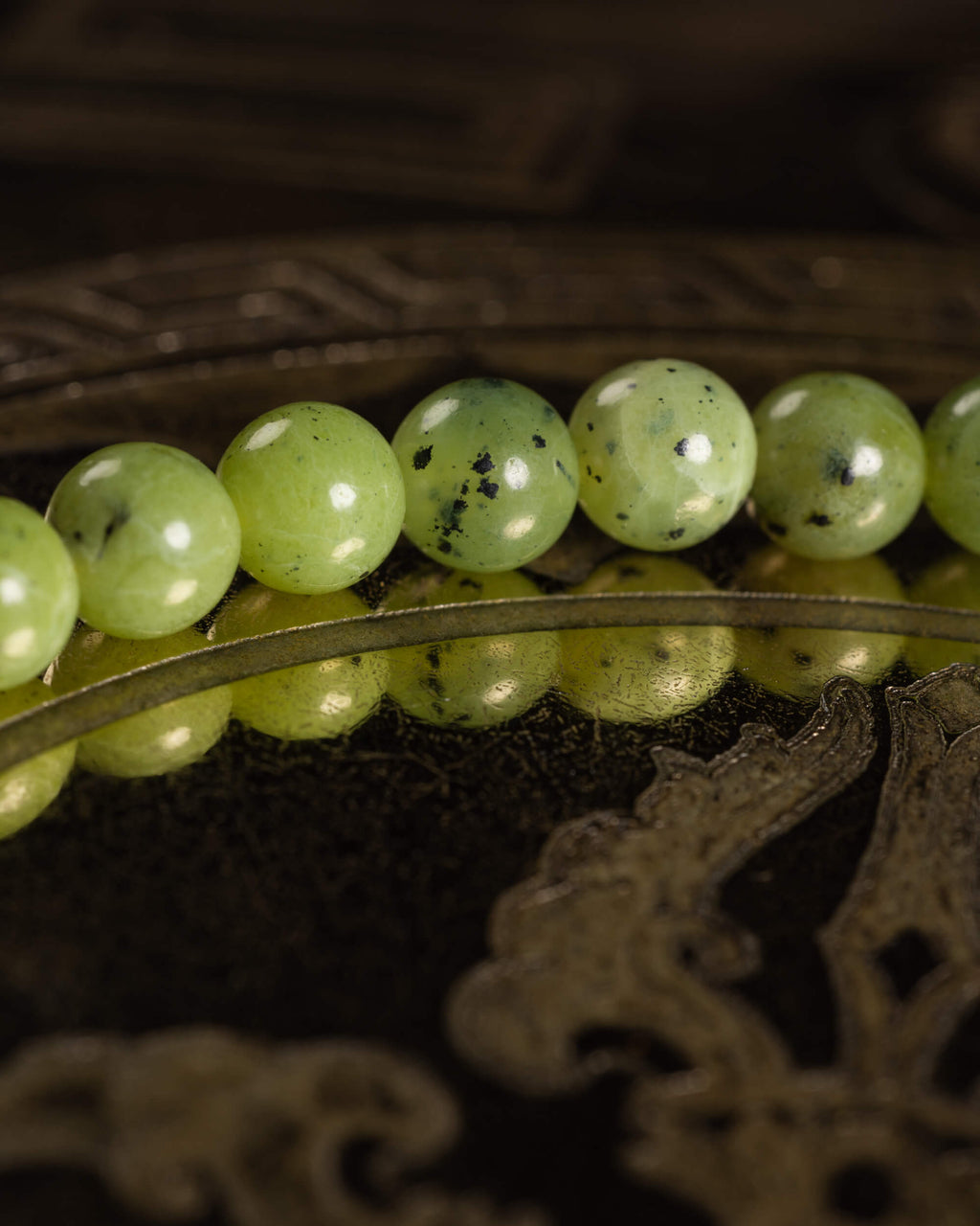 Detalle macro de las cuentas de Jade Verde con motas oscuras, textura pulida al brillo
