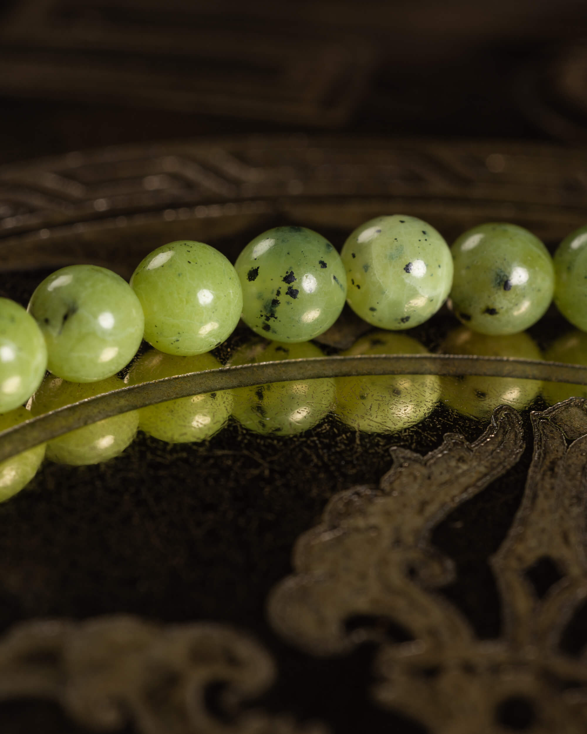 Detalle macro de las cuentas de Jade Verde con motas oscuras, textura pulida al brillo