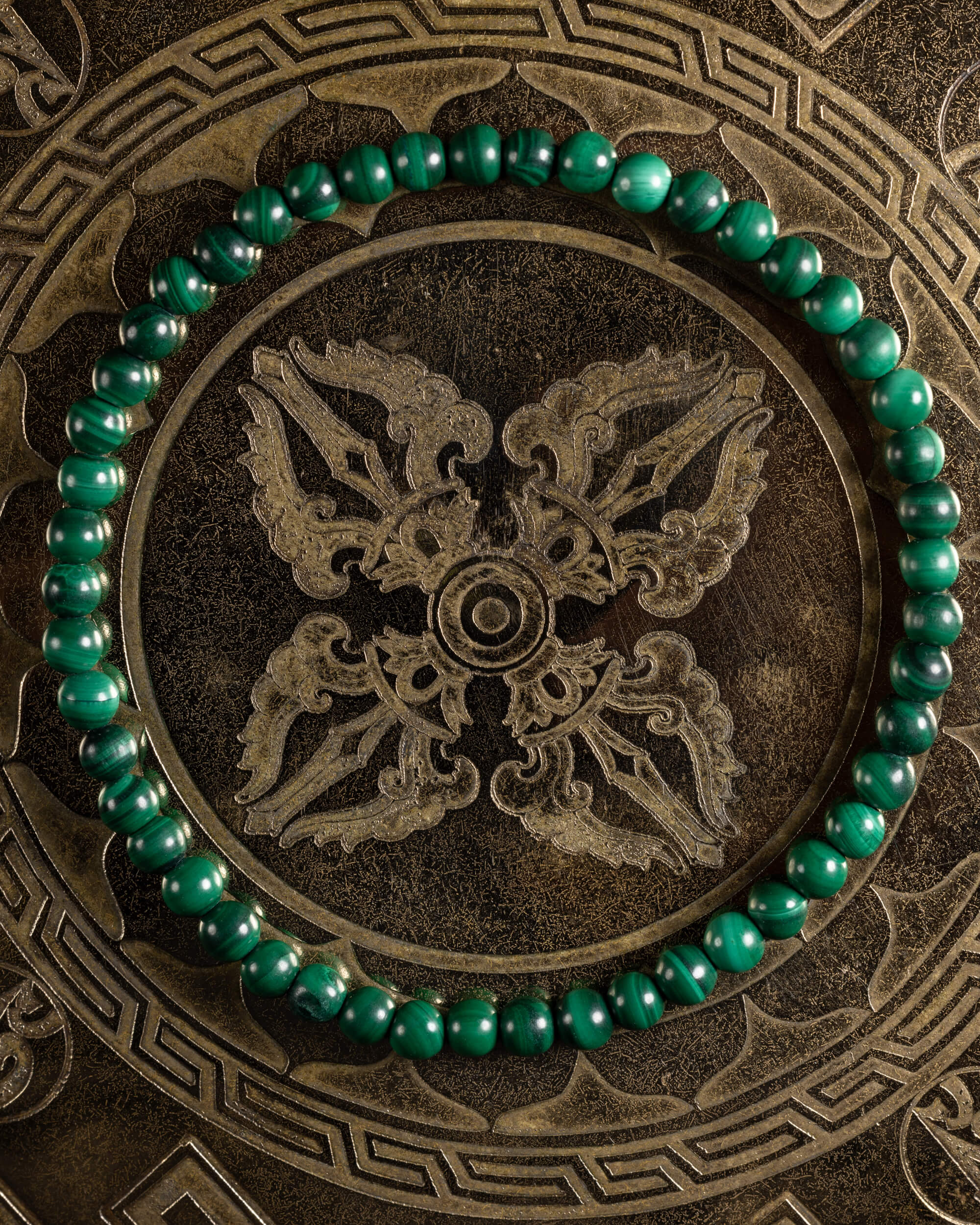 Pulsera de Malaquita de 4 mm, pieza completa en círculo sobre placa metálica grabada