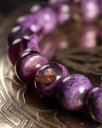 Pulsera de Lepidolita Violeta en curva, cuentas moradas sobre bandeja grabada