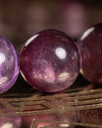Detalle macro de una cuenta de Lepidolita Violeta con vetas y textura natural