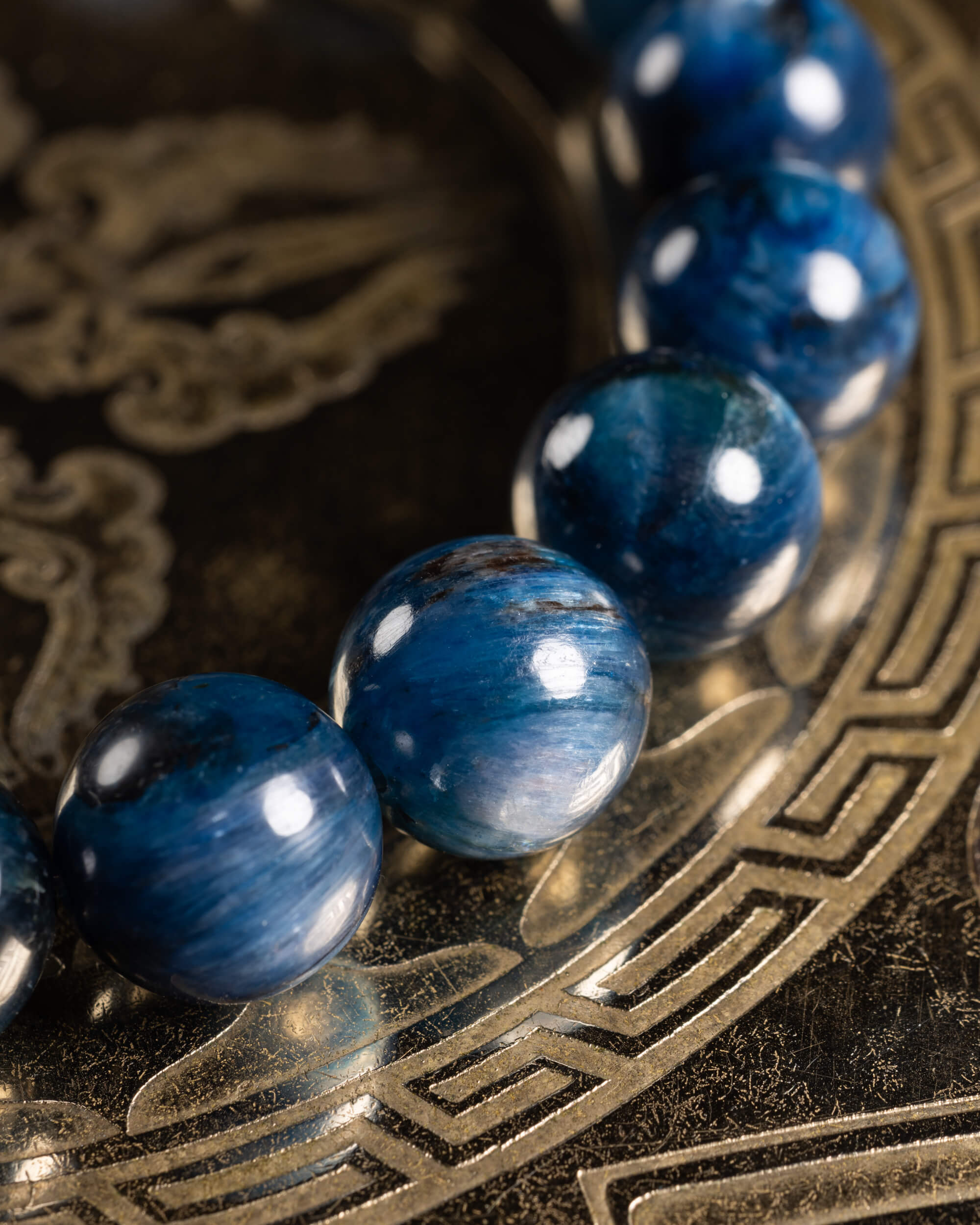 Pulsera de Cianita Azul en curva, cuentas azules con veta fibrosa sobre metal grabado