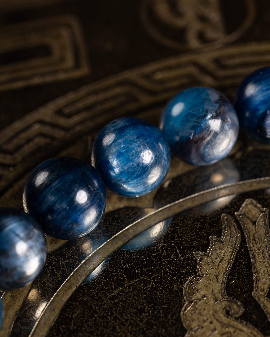 Pulsera de Cianita Azul en ángulo cercano sobre disco grabado con relieve dorado