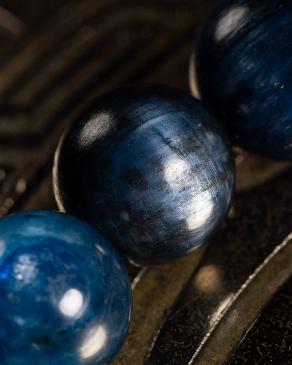Detalle macro de una cuenta de Cianita Azul con vetas oscuras y reflejo de luz