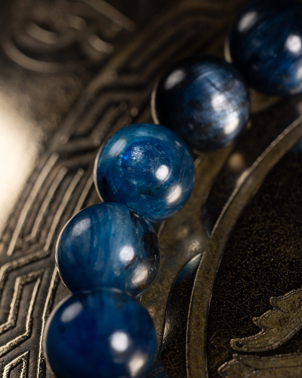 Detalle macro de las cuentas de Cianita Azul sobre superficie con grabado geométrico