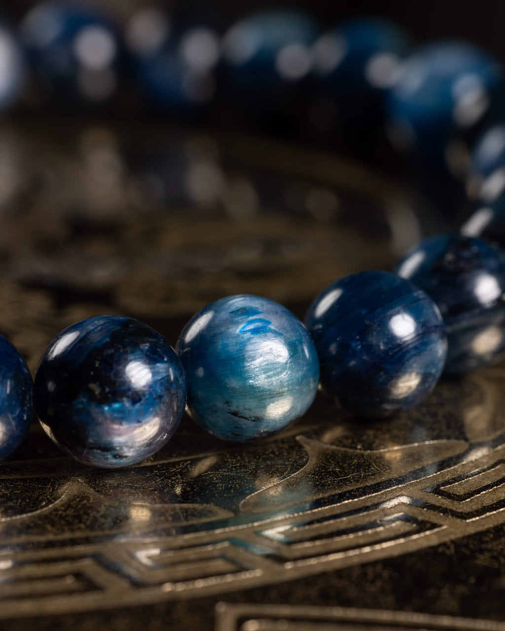 Detalle macro de las cuentas de Cianita Azul con la pulsera desenfocada al fondo