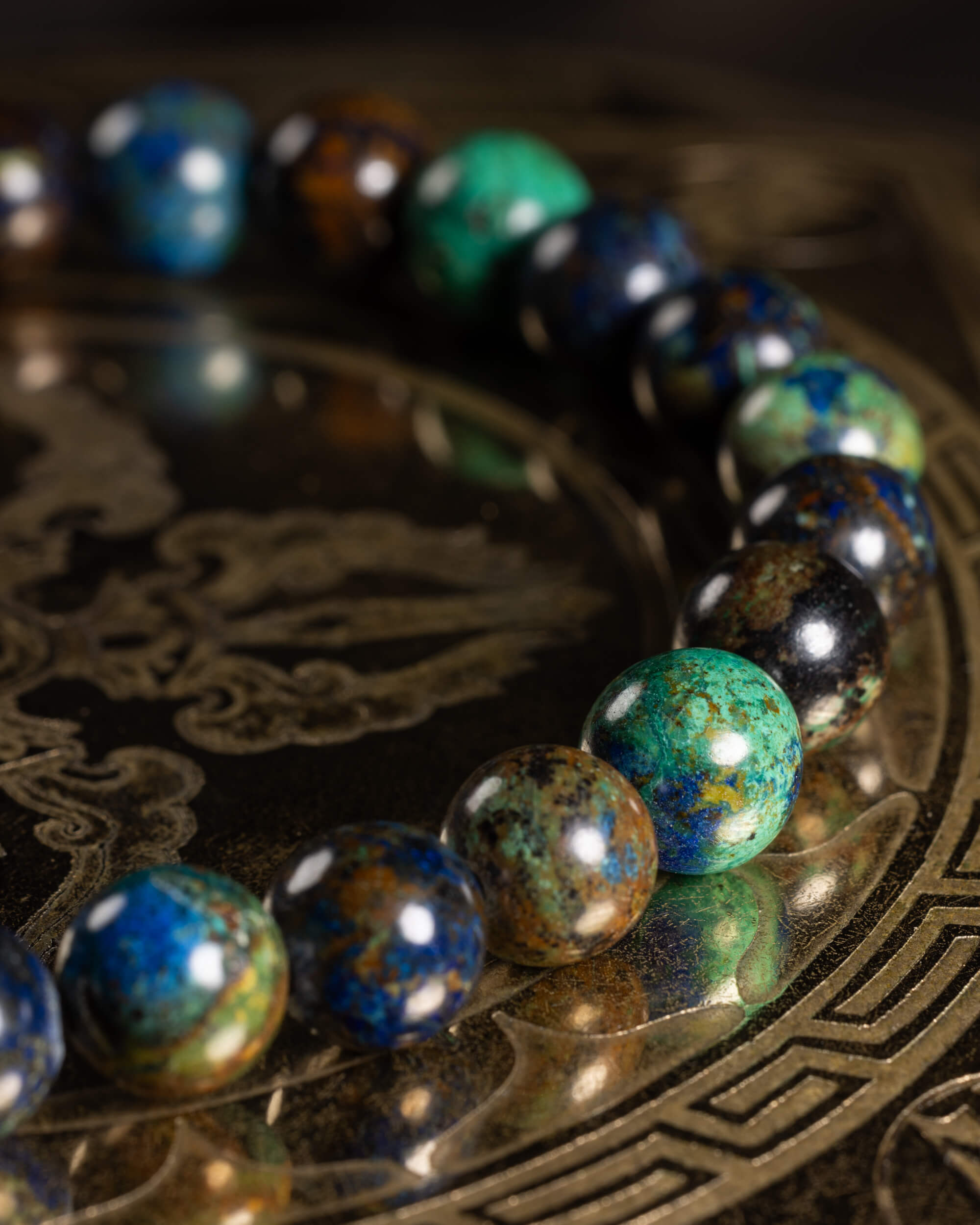 Pulsera de Crisocola en curva, cuentas azules y verdes con reflejos sobre metal grabado