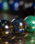 Detalle macro de tres cuentas de Crisocola con vetas cafés, azules y verdes