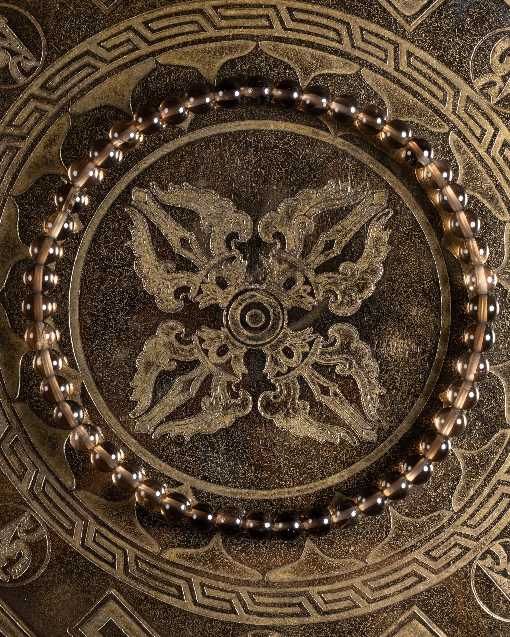 Pulsera de Cuarzo Ahumado de 4 mm, pieza completa sobre soporte grabado con motivos dorados