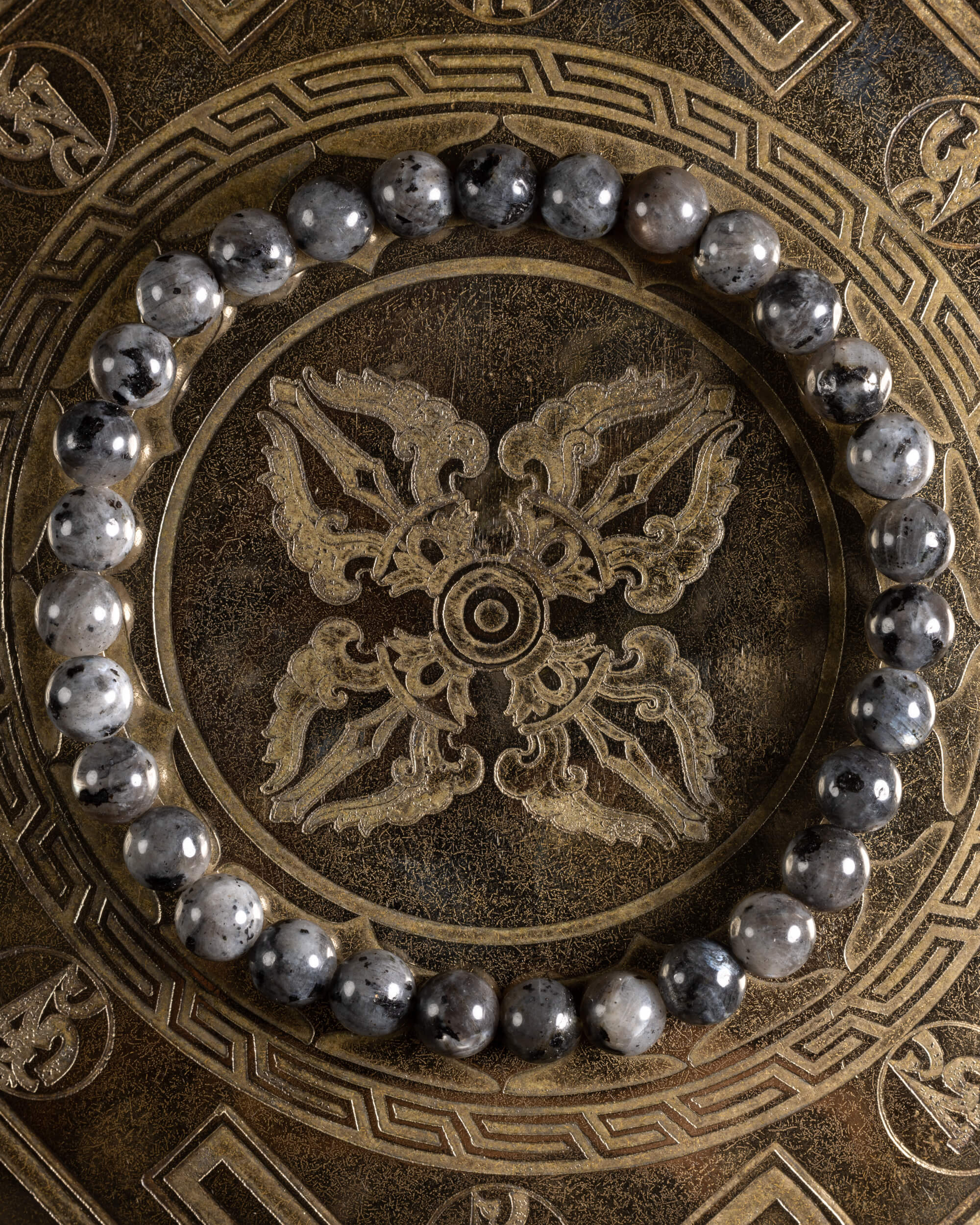 Pulsera de Larvikita de 6 mm, pieza completa en círculo sobre placa grabada dorada