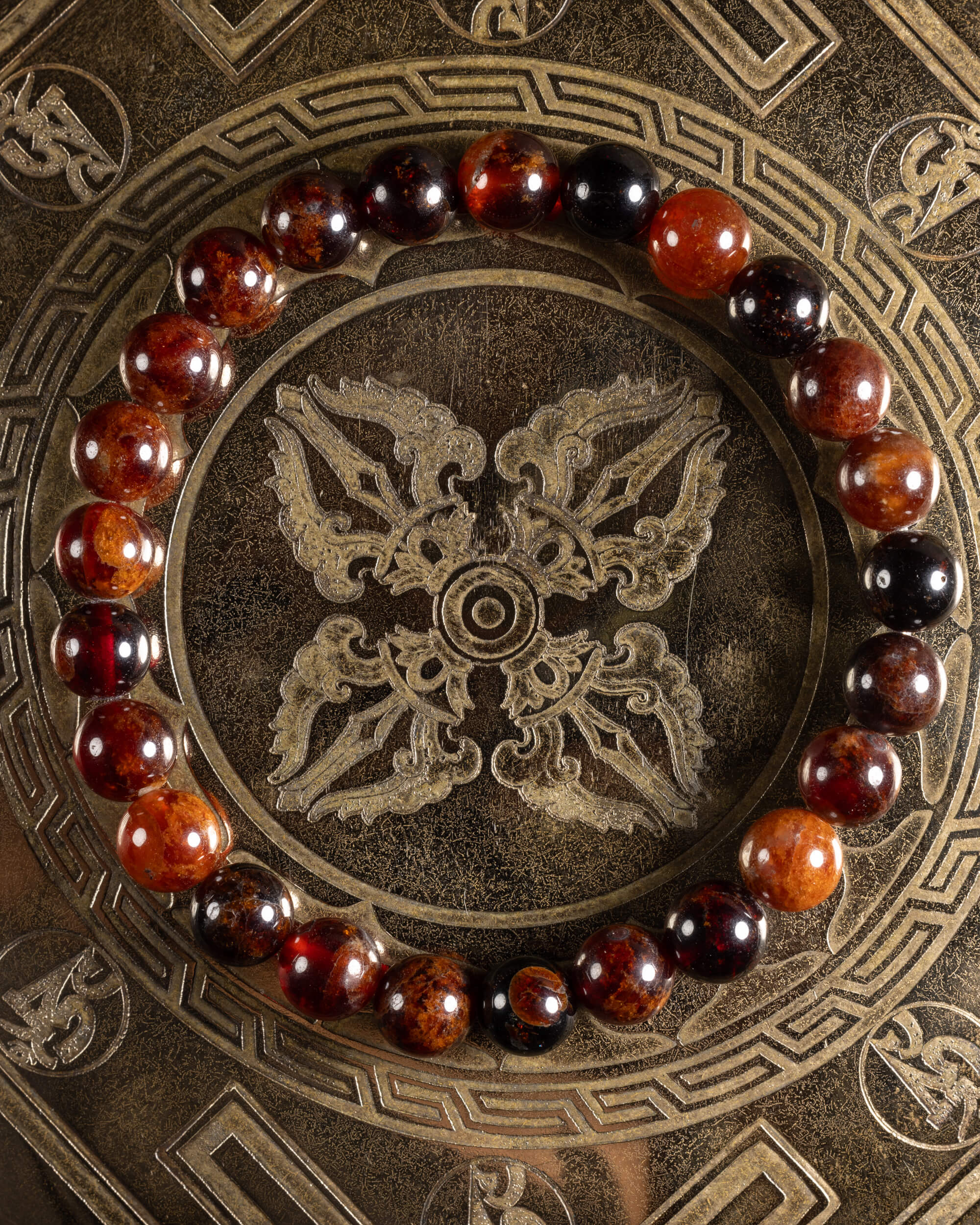 Pulsera de Granate Espesartina de 8 mm, pieza completa en círculo sobre placa grabada