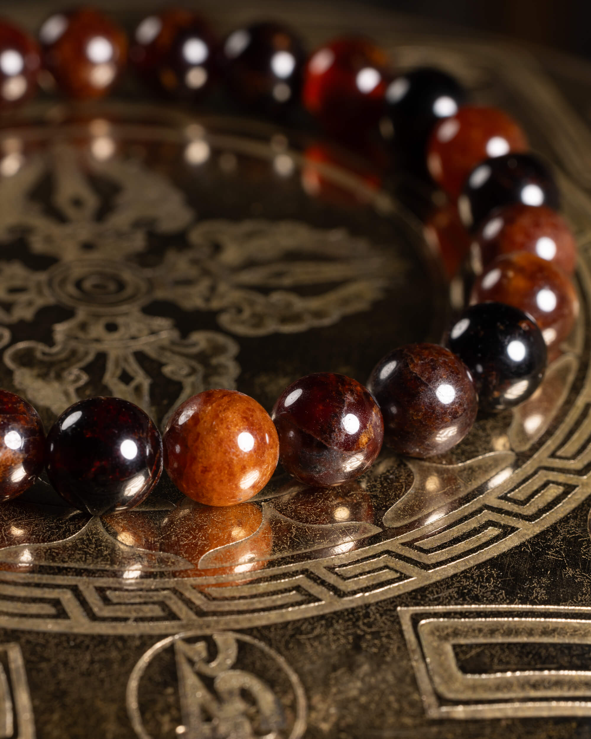 Pulsera de Granate Espesartina en curva sobre placa grabada, mezcla de tonos cálidos