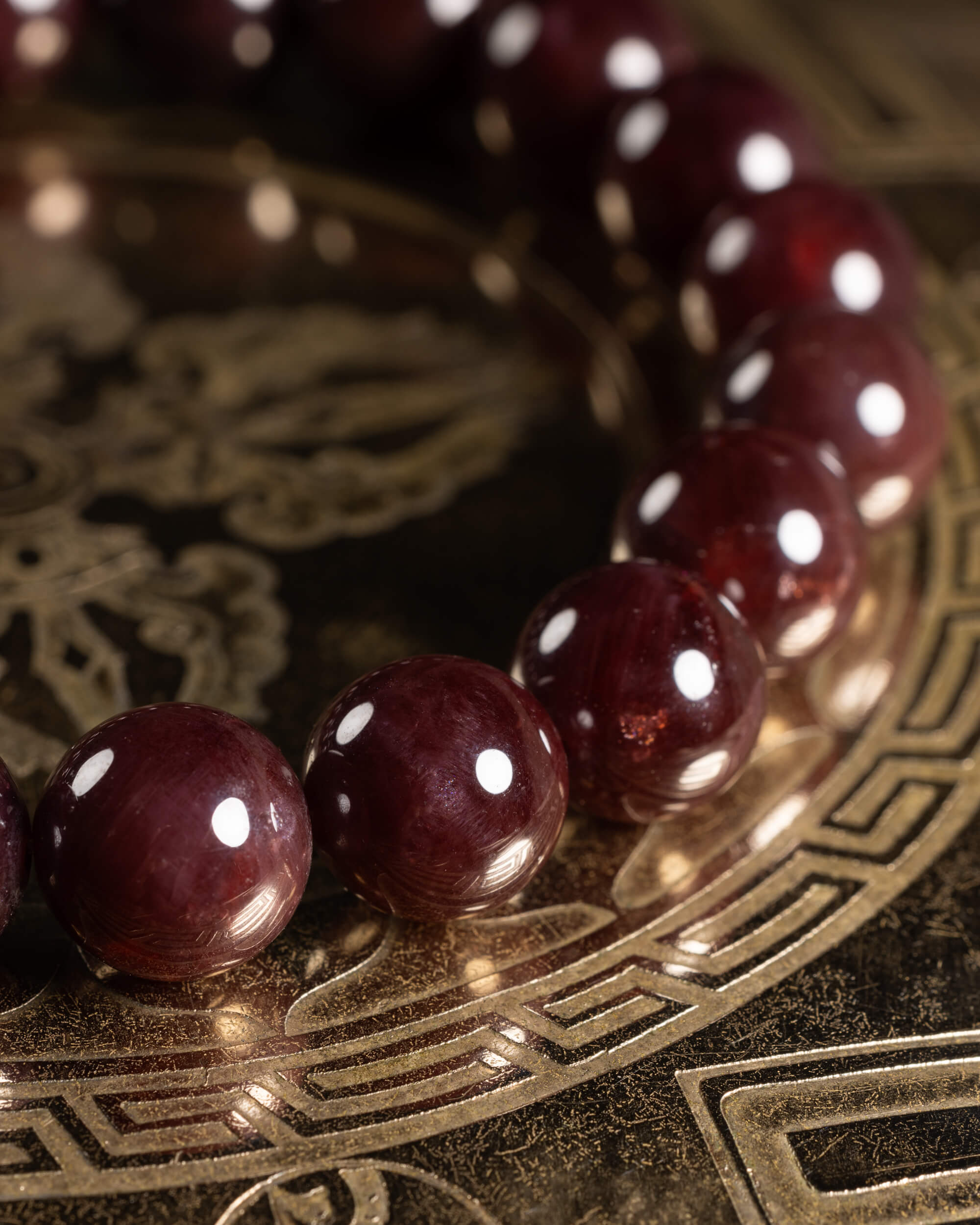 Pulsera de Granate Estrella en curva sobre placa dorada, cuentas de tono vino