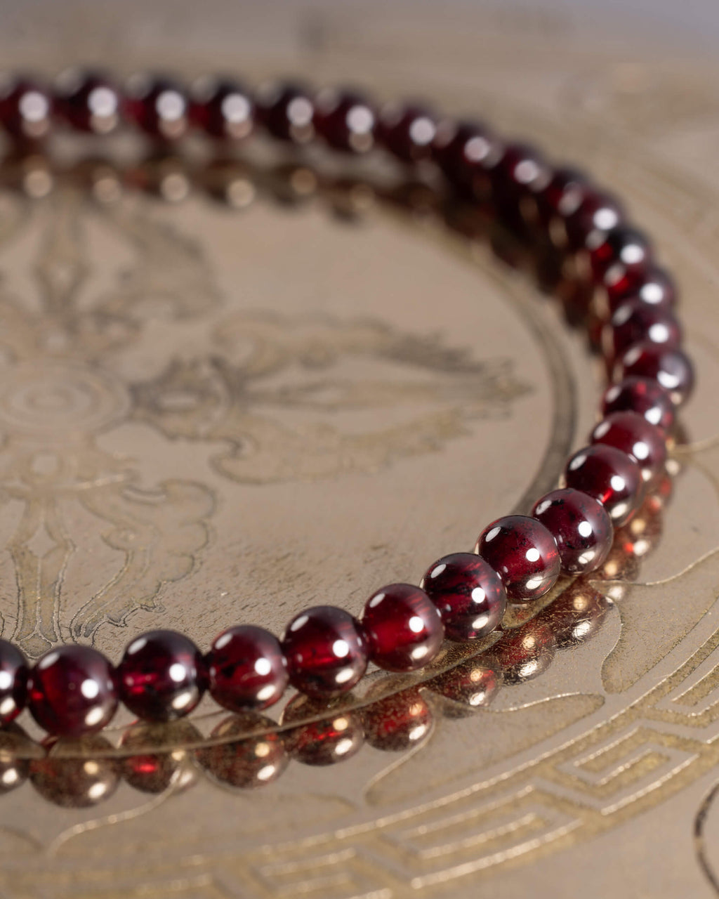 Pulsera de Granate Rojo en círculo sobre placa dorada grabada con motivos orientales