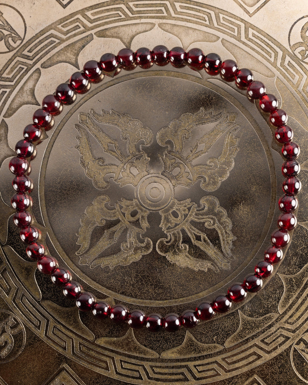 Pulsera de Granate Rojo de 4 mm, pieza completa en círculo sobre placa grabada dorada