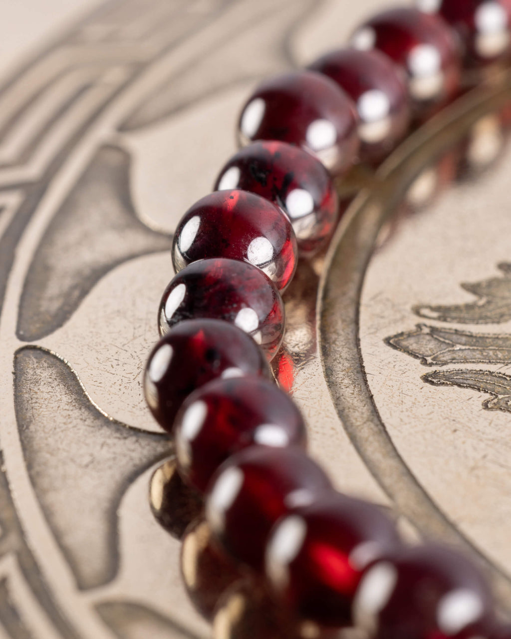 Pulsera de Granate Rojo en curva sobre placa grabada, cuentas de tono rojo intenso