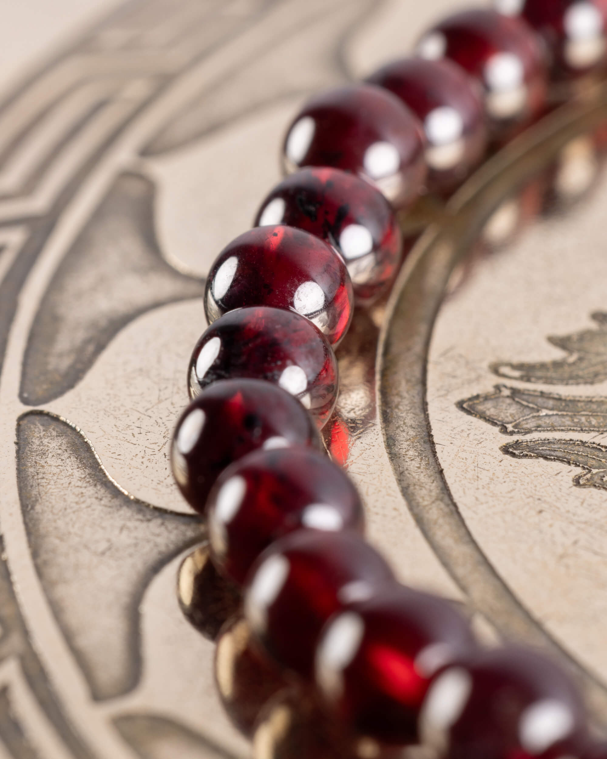 Pulsera de Granate Rojo en curva sobre placa grabada, cuentas de tono rojo intenso