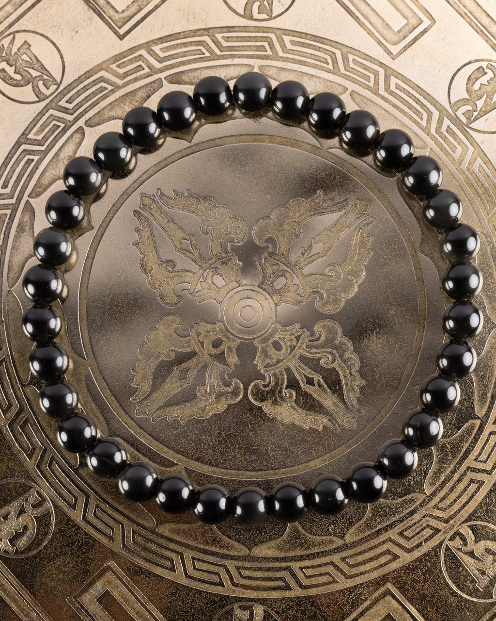 Pulsera de Obsidiana Arcoíris de 6 mm, pieza completa en círculo sobre bandeja grabada