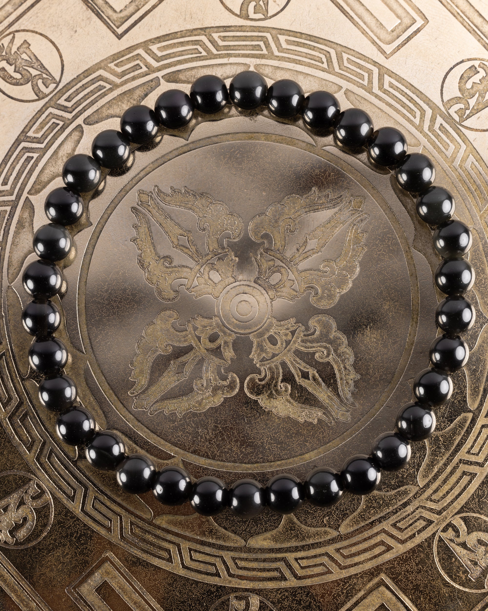 Pulsera de Obsidiana Arcoíris de 6 mm, pieza completa en círculo sobre bandeja grabada