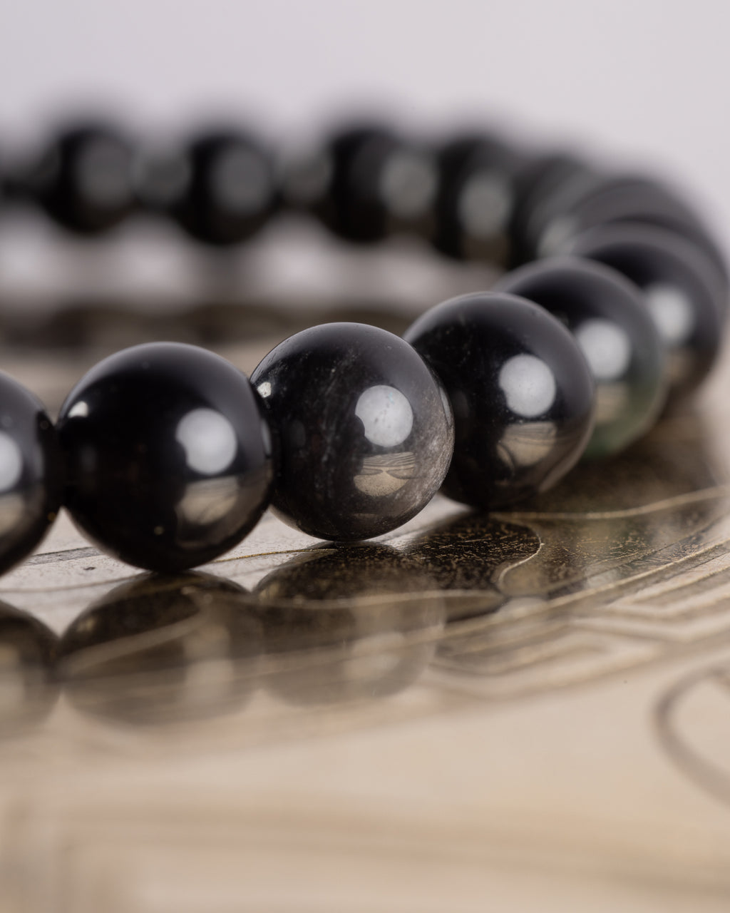 Detalle macro de las cuentas negras brillantes de Obsidiana Arcoíris