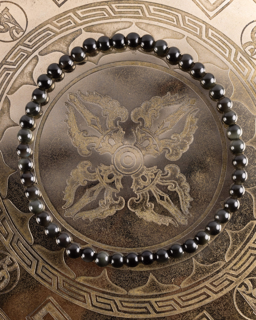 Pulsera de Obsidiana Negra de 4 mm, pieza completa en círculo sobre bandeja grabada