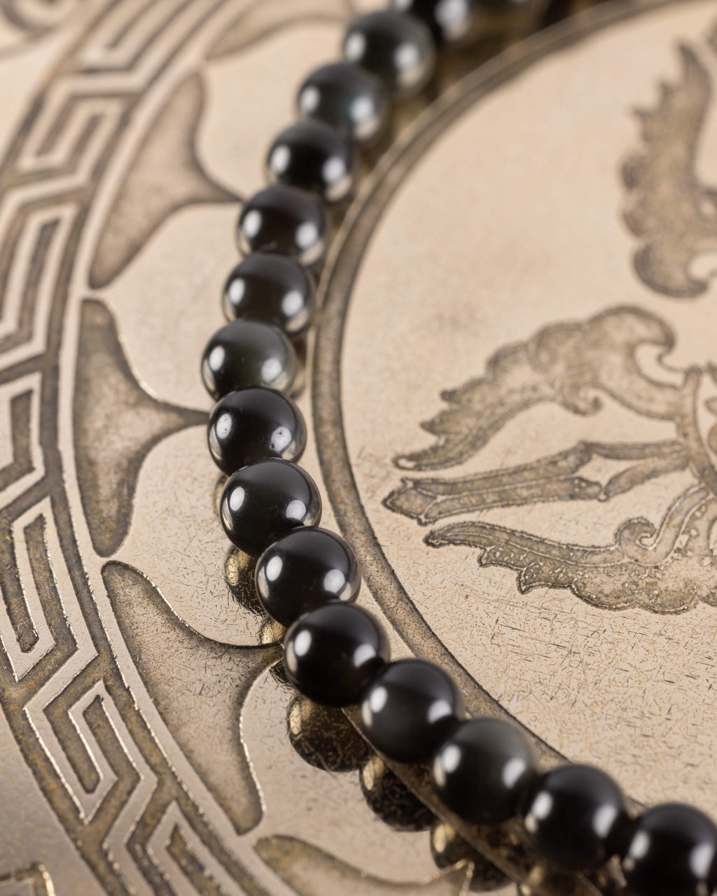 Pulsera de Obsidiana Negra en curva, cuentas pequeñas sobre bandeja grabada