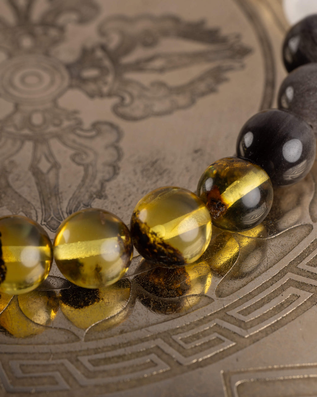 Detalle macro de las cuentas de Ámbar y Obsidiana Plateada de la pulsera Amaterasu