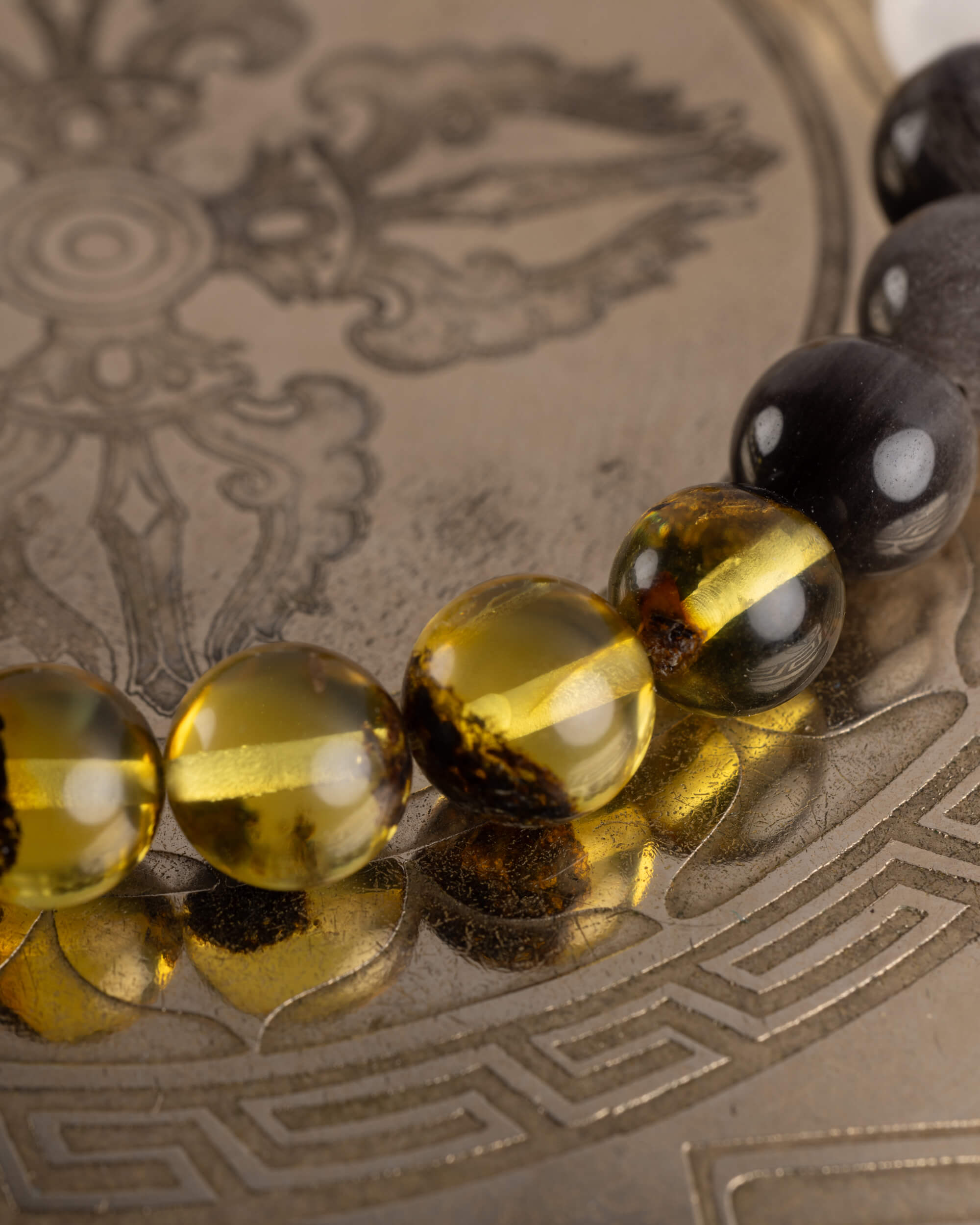 Detalle macro de las cuentas de Ámbar y Obsidiana Plateada de la pulsera Amaterasu