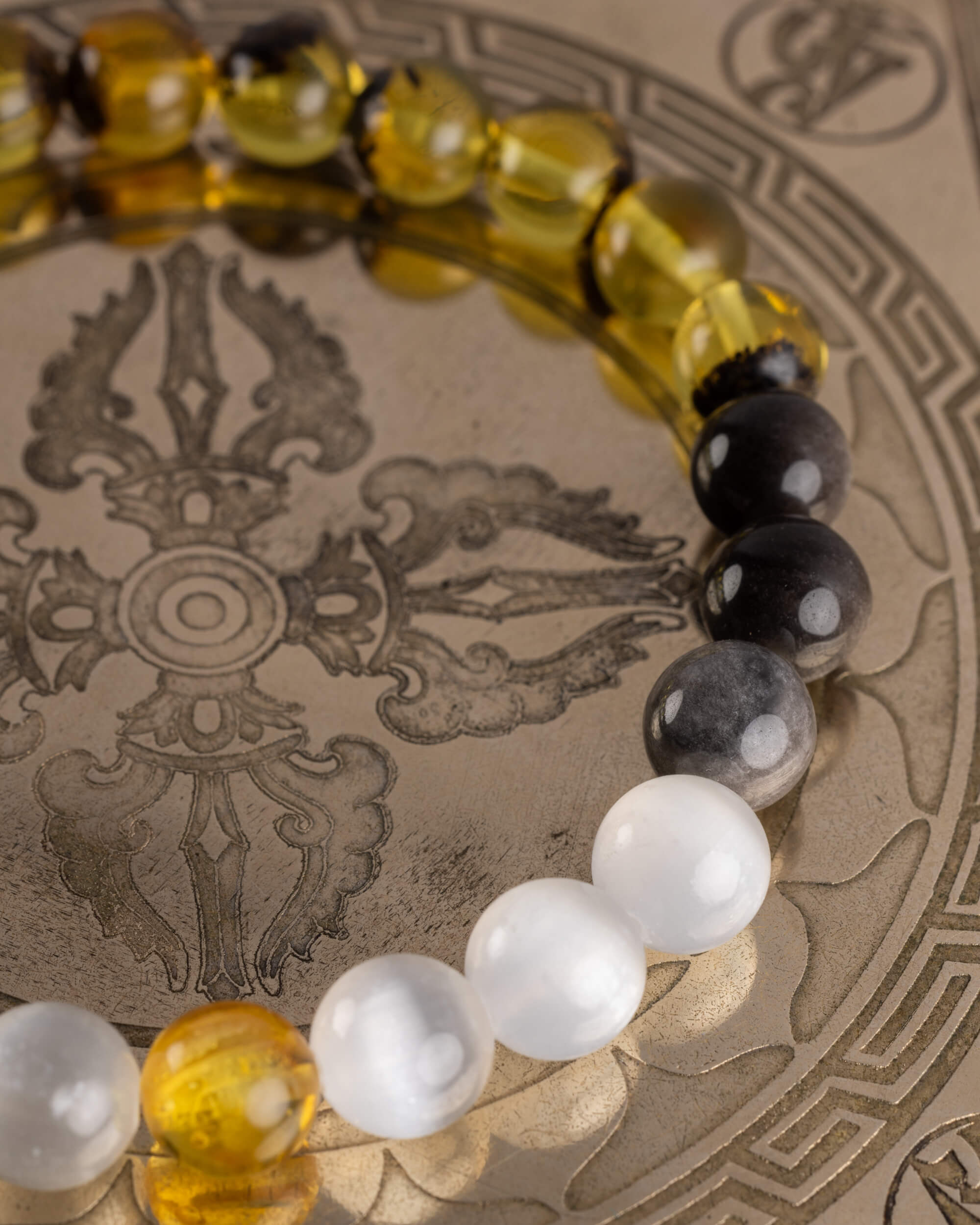 Detalle macro del recorrido de Ámbar, Obsidiana y Selenita de la pulsera Amaterasu