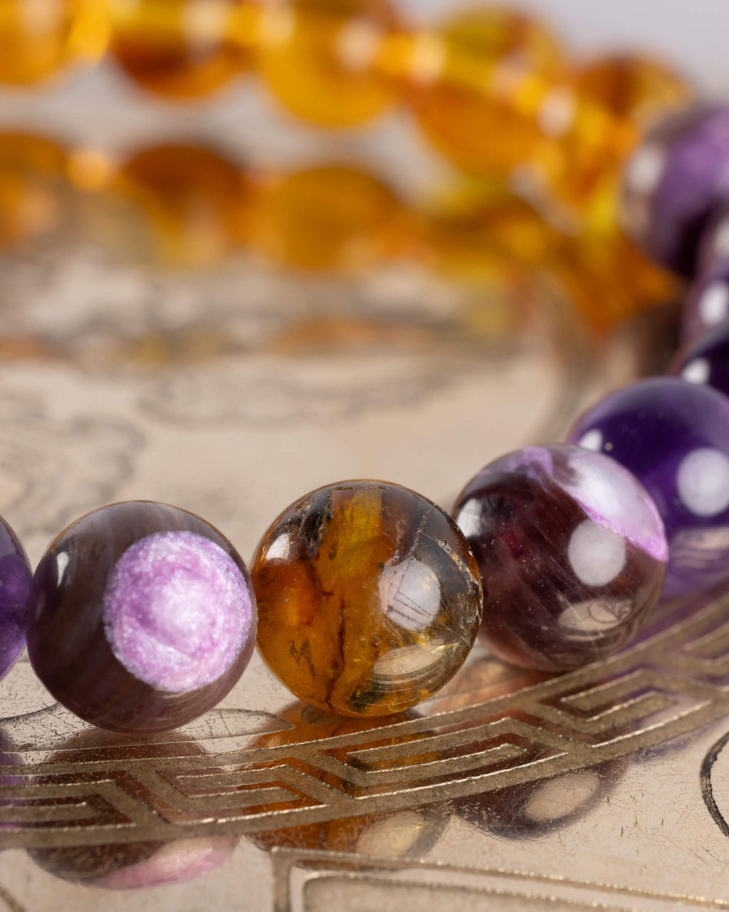 Detalle macro de una cuenta de Ámbar entre Lepidolita y Amatista de la pulsera Apolo