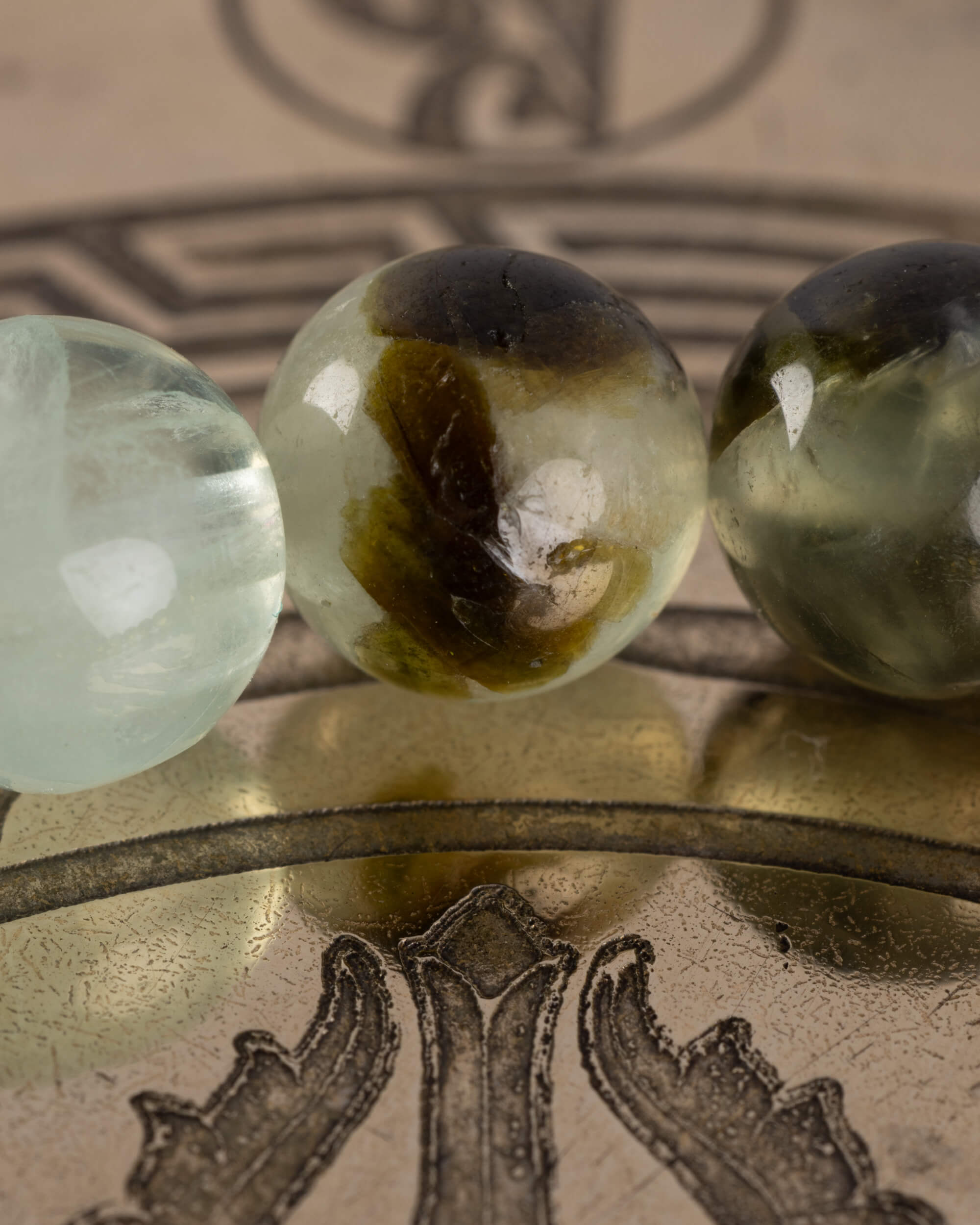 Detalle macro de cuentas verdes palidas y translucidas de Fluorita en la pulsera Surya, fondo borroso