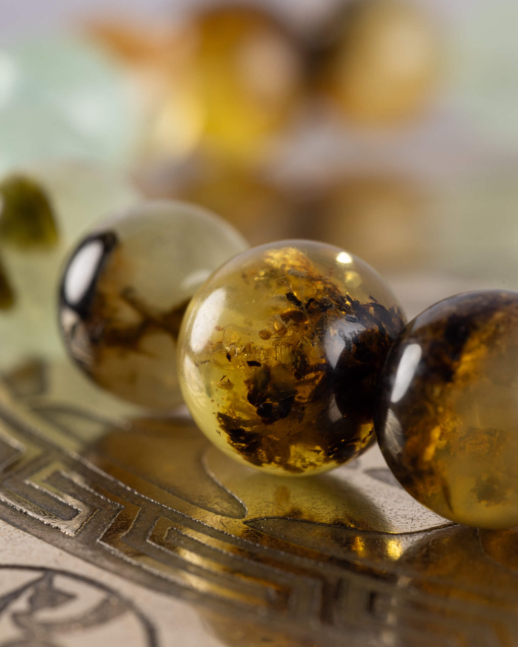 Detalle macro de cuentas doradas de Ámbar junto a una cuenta clara de la pulsera Surya