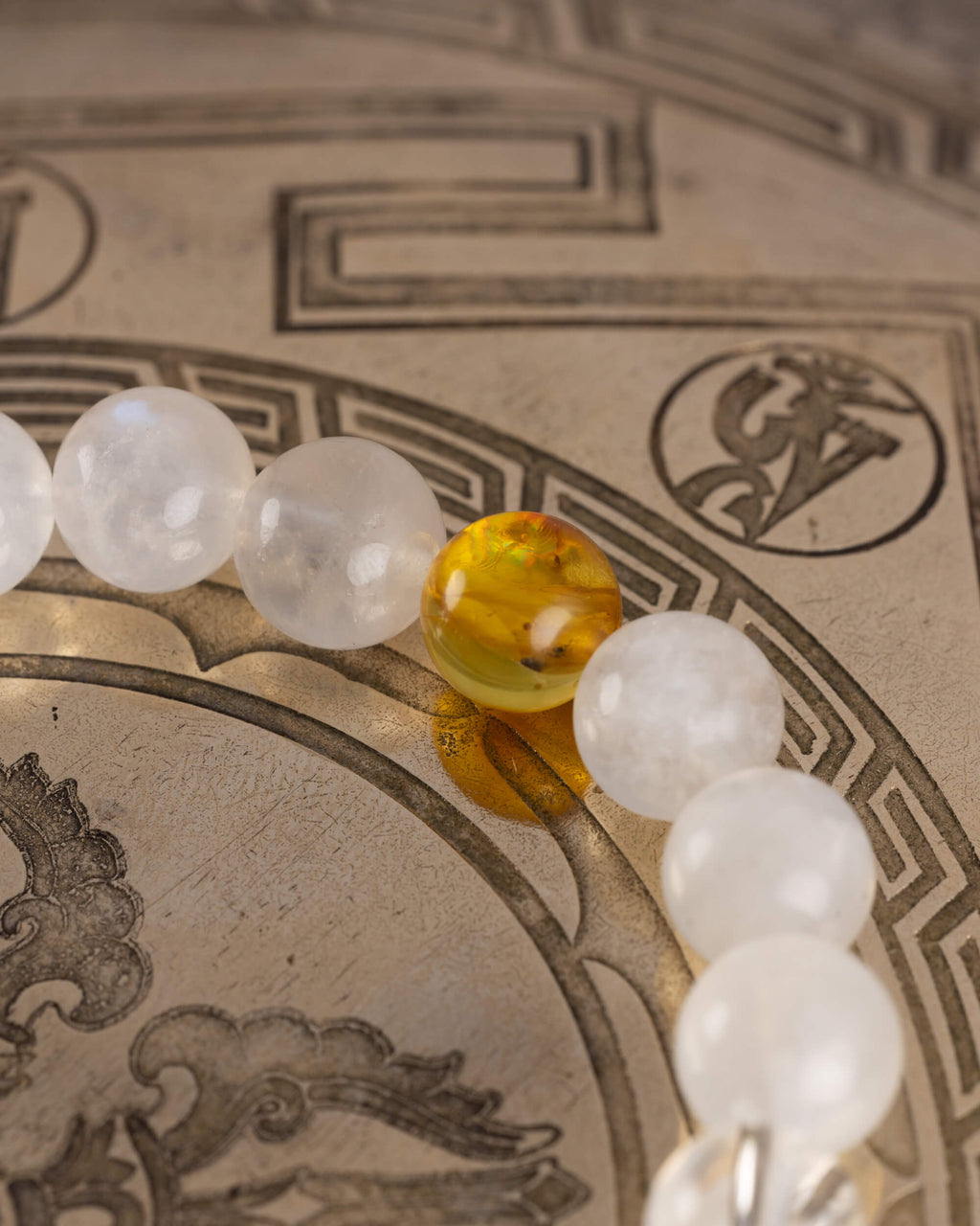 Detalle macro de una cuenta de Ámbar entre esferas de Piedra Luna de la pulsera Arinna