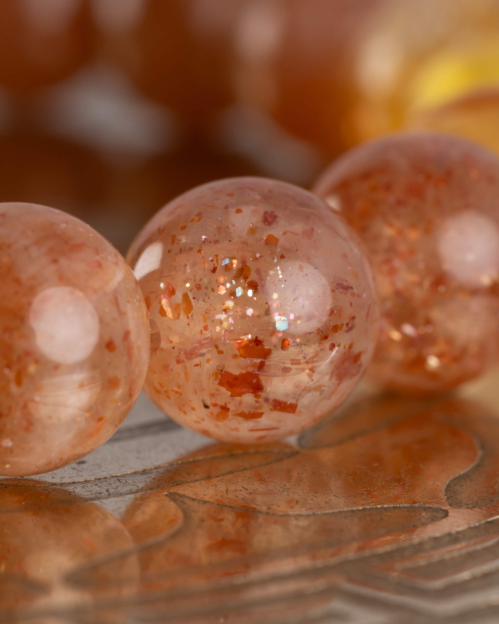 Detalle macro de las cuentas de Piedra Sol Roja con destellos de la pulsera Sol Invictus