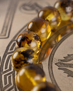 Detalle macro de las cuentas de Ámbar de la pulsera Saule sobre placa grabada