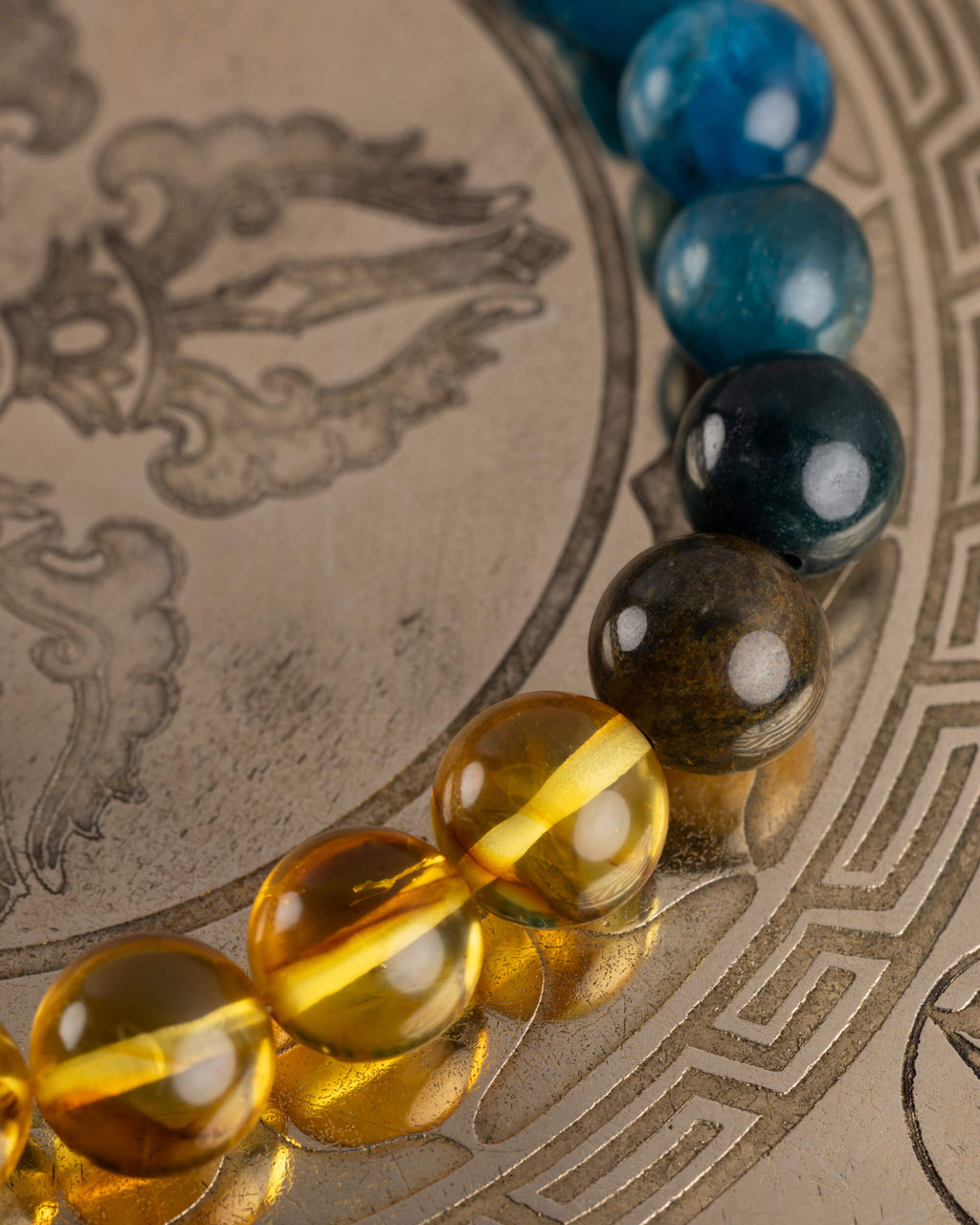Detalle macro de las cuentas de Ámbar de la pulsera Tamanuiterā sobre placa metálica