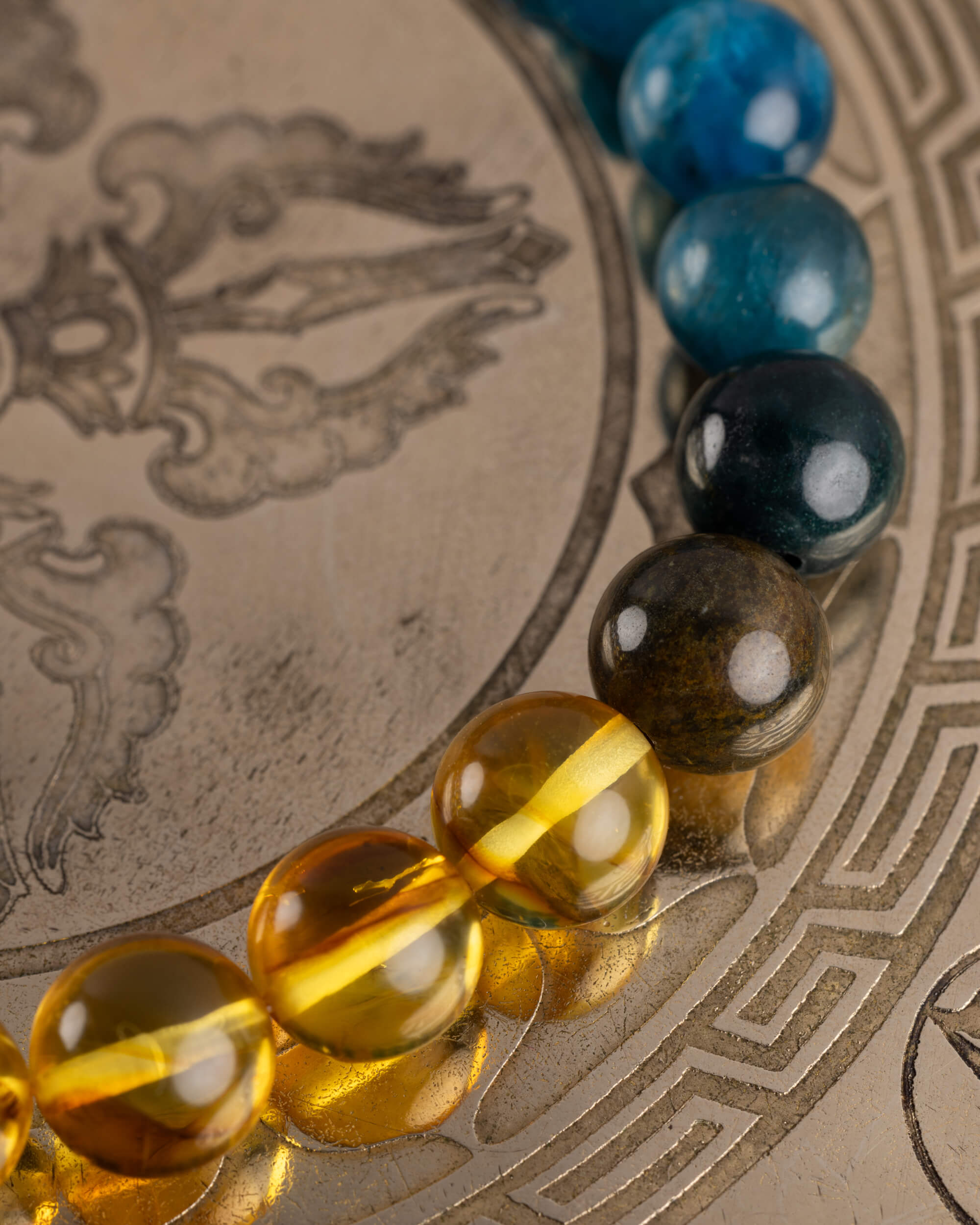 Detalle macro de las cuentas de Ámbar de la pulsera Tamanuiterā sobre placa metálica